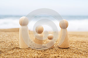 Wooden four figures of people on the sand of beach with sea view. Concept of happy family with two kids on holiday.