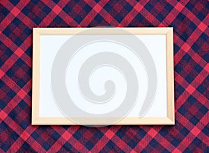 Wooden frame without drawing on a red plaid tablecloth