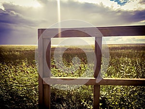 A wooden frame by grassy coast in summer