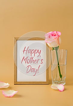 Wooden frame with greeting card text HAPPY MOTHERS DAY delicate pink roses on beige background. Minimal trendy