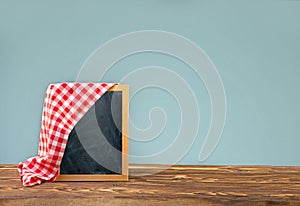Wooden frame with a red checkered tablecloth on the side for notes on a wooden table
