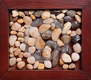 A wooden frame with sea pebbles, very close-up.