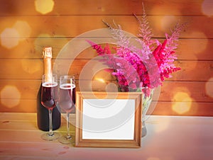 Wooden frame, two glasses of rose champagne, bottle of rose champagne and astilbe flowers