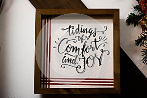 Wooden frame with the writing tidings of comfort and joy with black letters