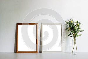 Wooden frames and green leaves on table with natural light.