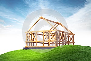 Wooden framing for construction of new house on grass on sky bac
