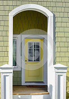 Wooden front yellow door of a home. Front view of a door on a house with the porch and front walkway