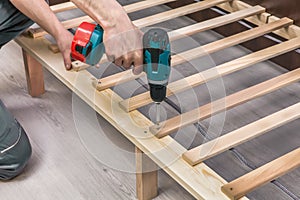 Wooden furniture assembling- woodworker screwing screws photo