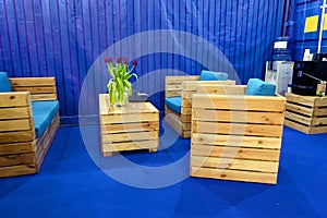 Wooden furniture from pallets in the office interior. Armchairs and coffee table on a blue background