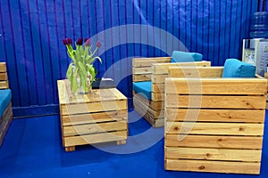 Wooden furniture from pallets in the office interior. Armchairs and coffee table on a blue background.