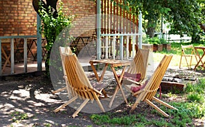 Wooden furniture set for Picnic in garden. Empty sun loungers and table on veranda of house in forest. outdoor furniture for leisu