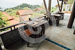 Wooden furniture on veranda cafe on background red roofs bungalow