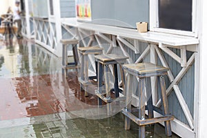 Wooden furniture on a wooden deck on the sidewalk near cafe and restaurant with nobody around during a morning time