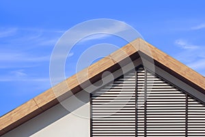 Wooden gable roof with battens decoration of retro house against cloud on blue sky background
