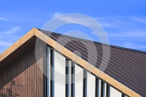 Wooden gable roof with battens decoration of vintage house against cloud on blue sky background