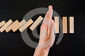 Wooden game strategy, hand stopping falling wooden dominoes effect of continuous overthrown or risk, strategy and successful inter