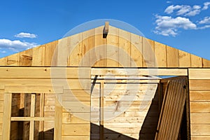 A wooden garden shed under construction standing on a concrete foundation in the garden, visible greenhouse.