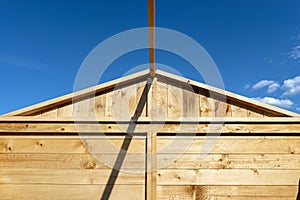 A wooden garden shed under construction standing on a concrete foundation in the garden, visible greenhouse.