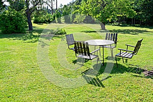 Wooden garden table and four chairs on a green lawn