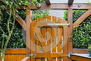 Wooden gate and fence on the back of the home garden. The gate is closed with a padlock.