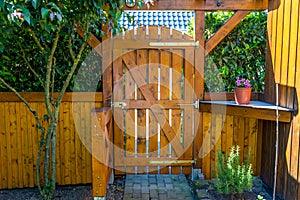 Wooden gate and fence on the back of the home garden. The gate is closed with a padlock.