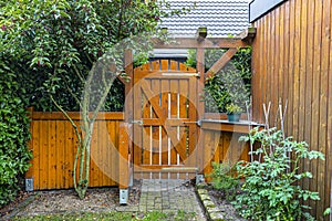 Wooden gate and fence on the back of the home garden. The gate is closed with a padlock.