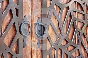 Wooden gate with forged metal elements. round metal handle close up. background texture