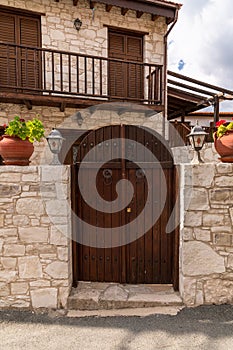 Wooden gate and stone fence in front of house in Cyprus