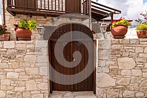 Wooden gate and stone fence in front of house in Cyprus