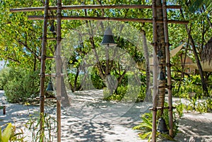 Wooden gates with metal bell near restaurant entrance at tropical island
