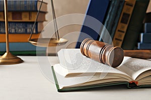 Wooden gavel, scales of justice and books on table