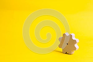 A wooden gear on a yellow background. The concept of technology and business processes. Minimalism. Mechanisms and devices. Work,