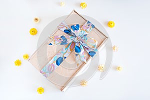 Wooden gift box with bow and yellow flowers on light background.