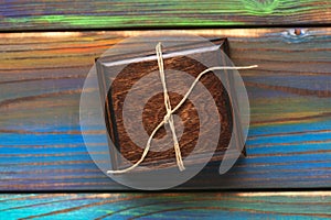 Wooden gift box on multicolored textured background. Jewelry box tied with a rope