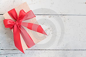 Wooden gift box with red ribbon bow on vintage background