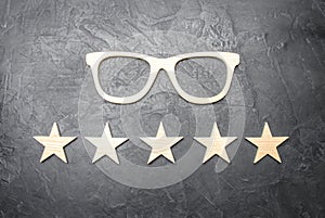 Wooden glasses and five stars on a concrete background. High quality glasses. The best optics. Correction of vision