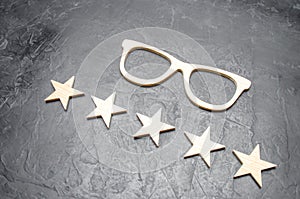 Wooden glasses and five stars on a concrete background. High quality glasses. The best optics. Correction of vision