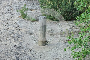 Wooden gray pillar stands in the sand