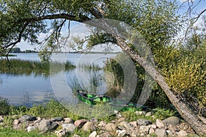 Wooden green boat, old fishing vessel on the coast of tranquil lake, sustainable ecological tourism in Europe