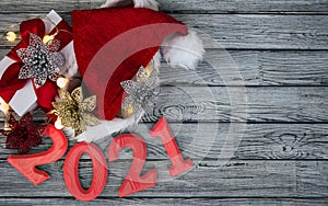 Wooden grey background with Christmas decorations,  lights, present and number 2021 for an happy new year