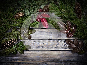 Wooden grey vintage background decorated with Christmas fir tree, fir cones and holly leaves. Free space for text. Empty template