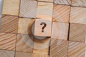 Wooden grid with standout engraved cube at center featuring a question mark photo