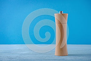 Wooden grinder for salt or pepper on blue background