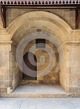 Wooden grunge door and window covered with interleaved wooden grid in recessed stone bricks wall, Cairo, Egypt photo