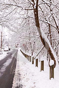 Wooden guardrails covered in snow next to a street on a snowy winter day