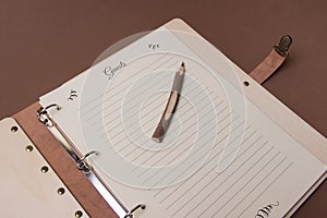 Wooden guests book with pen on brown colored paper background. close up