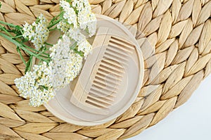 Wooden hairbrush (comb) and yarrow flowers. Eco friendly toiletries, natural hair care, homemade spa, beauty treatment
