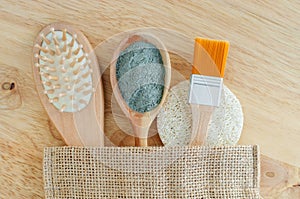 Wooden hairbrush, spoon with blue bentonite clay powder, make-up brush and loofah sponge. Natural beauty treatment