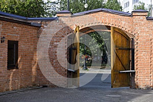 Wooden half-open gate in a brick fence in the courtyard of the 19th century merchant Kazakov house in Kazan, Russia