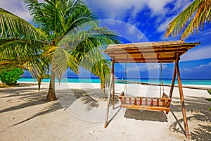 Wooden hammok and palms with tropical lagoon